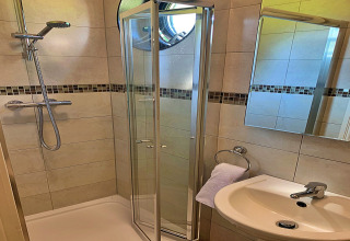 Salle de bain moderne dans un mobil-home à Oak Tree Lodge, Royaume-Uni, avec douche, lavabo et miroir.
