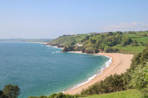 Vue panoramique depuis le mobil-home Oak Tree Lodge au Royaume-Uni, plage de sable, mer et collines vertes.