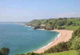 Vue panoramique depuis le mobil-home Oak Tree Lodge au Royaume-Uni, plage de sable, mer et collines vertes.