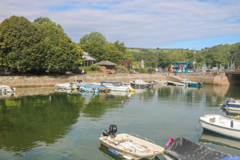 Scène portuaire à Oak Tree Lodge, Royaume-Uni, avec bateaux, arbres verts et un bus à l’arrière-plan.