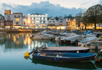 Veduta serale di barche ormeggiate nel porto con edifici illuminati da Oak Tree Lodge, Regno Unito.