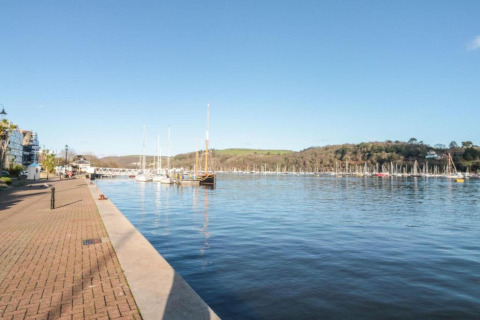 Vue d’un port paisible avec voiliers depuis Oak Tree Lodge au Royaume-Uni, sous un ciel bleu clair.