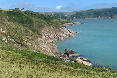 Vue depuis Oak Tree Lodge au Royaume-Uni avec falaises verdoyantes, mer bleue et ciel dégagé.