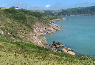 Vue depuis Oak Tree Lodge au Royaume-Uni avec falaises verdoyantes, mer bleue et ciel dégagé.