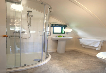 Lichte badkamer met ronde douche en wastafel in de Barebones Glamping-pod in het Verenigd Koninkrijk.