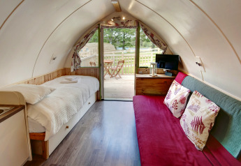 Binnenzicht van de Humbleton Glamping pod in het Verenigd Koninkrijk met bed, zetel en terras buiten.