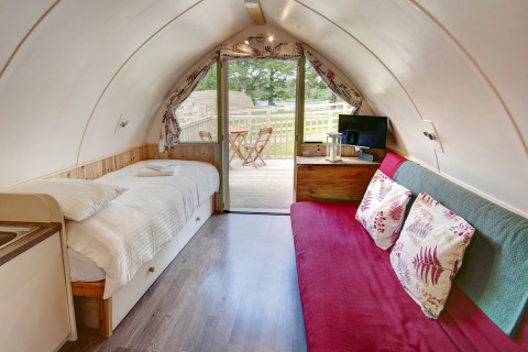 Interieur van Humbleton Glamping pod in het Verenigd Koninkrijk met bed, bank en buitenterras.