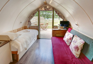 Interieur van Humbleton Glamping pod in het Verenigd Koninkrijk met bed, bank en buitenterras.