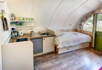 Binnenzicht van Humbleton Glamping pod met een bed, compacte keuken en houten vloer in het VK.