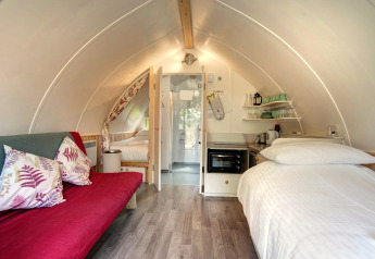 Binnenzicht van Humbleton Glamping pod in het Verenigd Koninkrijk met bed, sofa en kitchenette.