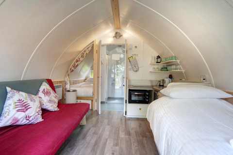 Binnenaanzicht van Humbleton Glamping pod in het Verenigd Koninkrijk met bed, bank en kitchenette.