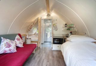 Binnenaanzicht van Humbleton Glamping pod in het Verenigd Koninkrijk met bed, bank en kitchenette.