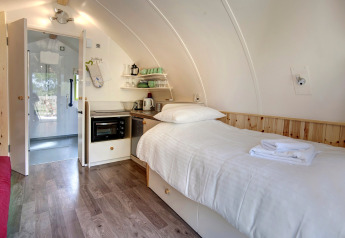 Modern glampingpod-interieur met een enkel bed, kitchenette en badkamer bij Humbleton Glamping, VK.