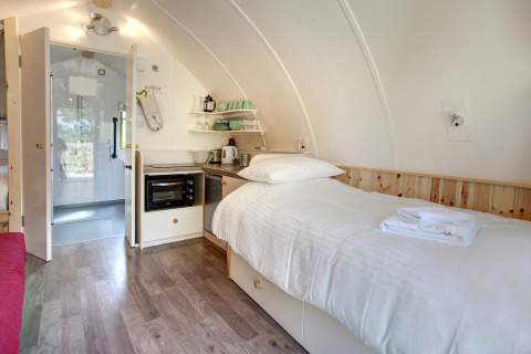 Modern glampingpod-interieur met eenpersoonsbed, kitchenette en badkamer bij Humbleton Glamping, VK.