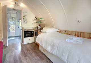Modern glampingpod-interieur met eenpersoonsbed, kitchenette en badkamer bij Humbleton Glamping, VK.
