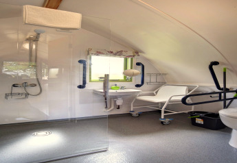 Toegankelijke badkamer in de Humbleton Glamping pod, met douche, handgrepen en rolstoelstoel.