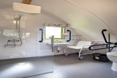 Toegankelijke badkamer in Humbleton Glamping pod, met douche, beugels en verrijdbare douchestoel.
