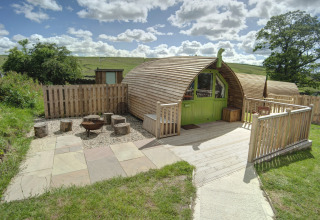 Houten glampingpod met groene deur bij Humbleton Glamping, Verenigd Koninkrijk, omgeven door natuur.