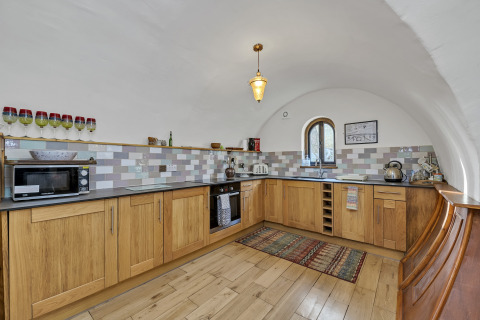 Cucina moderna con mobili in legno, soffitto a volta e piastrelle nel Pod 'Hollow' nel Regno Unito.