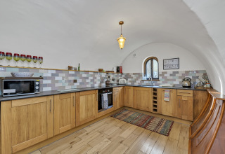 Cucina moderna con mobili in legno, soffitto a volta e piastrelle nel Pod 'Hollow' nel Regno Unito.