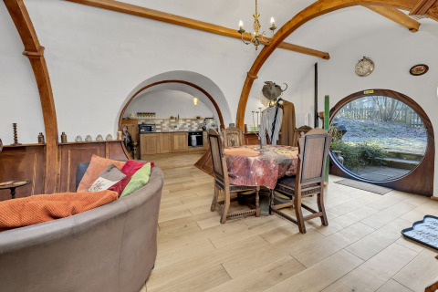 Interno di Pod 'Hollow' nel Regno Unito con soffitto arcuato, porte tonde e accogliente zona pranzo.