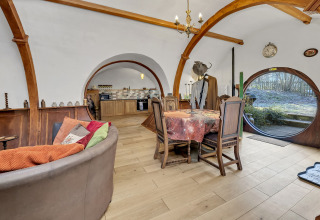 Interno di Pod 'Hollow' nel Regno Unito con soffitto arcuato, porte tonde e accogliente zona pranzo.