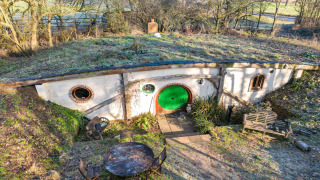 Pod Hollow, een huisje in hobbitstijl met een grasdak en een ronde groene deur, deels ondergronds.
