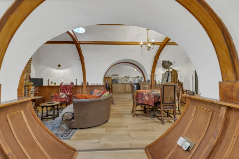 Vista interna del Pod 'Hollow' nel Regno Unito con archi in legno, salotto accogliente e zona pranzo.