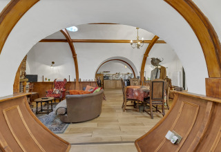 Vista interna del Pod 'Hollow' nel Regno Unito con archi in legno, salotto accogliente e zona pranzo.