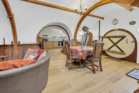 Interno del Pod Hollow nel Regno Unito con travi curve in legno, porta rotonda e arredo accogliente.