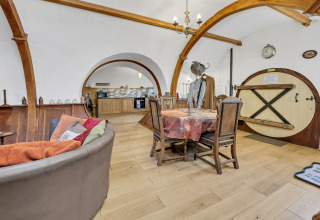 Interno del Pod Hollow nel Regno Unito con travi curve in legno, porta rotonda e arredo accogliente.