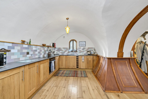 Cucina moderna nel pod 'Hollow' nel Regno Unito con soffitto a volta e piastrelle in tonalità pastello.