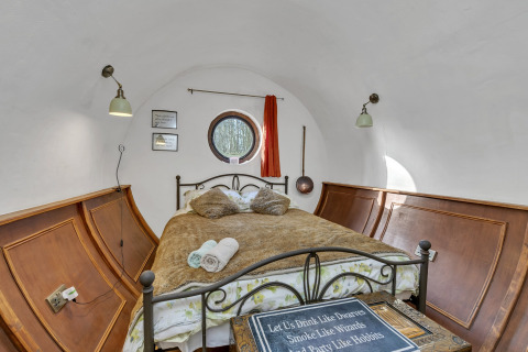 Accogliente stanza pod nel Regno Unito con pareti curve, letto matrimoniale, pannelli in legno e finestra tonda.