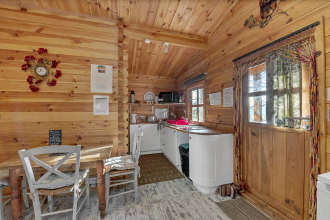 Cozy wooden interior of Woodland Lodge chalet in the UK, featuring a dining nook and compact kitchenette.