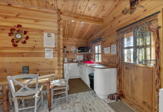 Cozy wooden interior of Woodland Lodge chalet in the UK, featuring a dining nook and compact kitchenette.