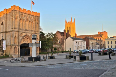 Glampinglocatie met uitzicht op historische gebouwen en een kathedraal in een charmante Engelse stad bij zonsondergang.