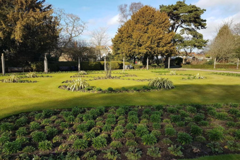 Goed onderhouden tuin met groene grasvelden en struiken bij een glampingaccommodatie in de zon.