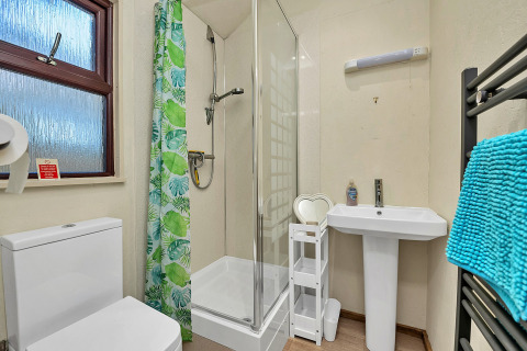 Moderne badeværelse i Cedar Lodge, Storbritannien, med bruser, toilet og håndklæder i blå farve.