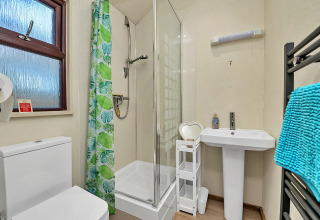 Moderne badeværelse i Cedar Lodge, Storbritannien, med bruser, toilet og håndklæder i blå farve.