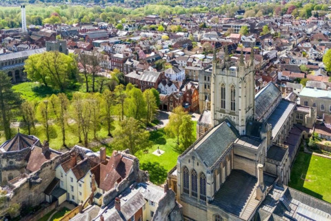 Luchtfoto van een sfeervol stadje met kathedraal en park, genomen vanaf een glamping accommodatie.