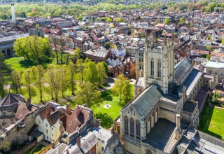 Luchtfoto van een sfeervol stadje met kathedraal en park, genomen vanaf een glamping accommodatie.