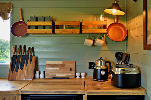 Moderne keuken in een mobiel huisje met houten aanrecht, pannen en apparaten in 'Joan' Shepherds Hut, VK.
