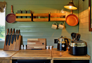 Moderne keuken in een mobiel huisje met houten aanrecht, pannen en apparaten in 'Joan' Shepherds Hut, VK.