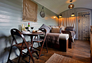 Knusse woonwagen met houten interieur, eethoek, wijn en bed in ‘Joan’ Shepherds Hut, Verenigd Koninkrijk.