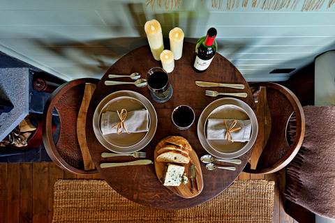 Gezellige tafel voor twee met kaarsen, wijn, brood en kaas in 'Joan' Shepherds Hut, Verenigd Koninkrijk.