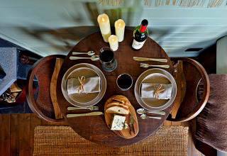Gezellige tafel voor twee met kaarsen, wijn, brood en kaas in 'Joan' Shepherds Hut, Verenigd Koninkrijk.
