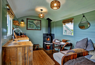 Knus interieur in mobiel huis 'Joan' Shepherds Hut in het Verenigd Koninkrijk met houtkachel en zithoek.