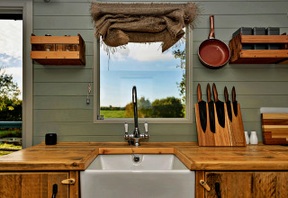 Landelijke keuken in de mobiele 'Joan' Shepherds Hut, VK, houten werkblad en uitzicht naar buiten.