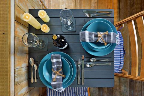 Tavola apparecchiata per due con piatti blu, tovaglioli a righe e candele al mobil home 'Susanna' Poachers Hut UK.