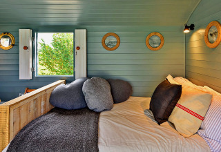 Accogliente zona notte nella 'Susanna' Poachers Hut con cuscini e pareti in legno, Regno Unito.